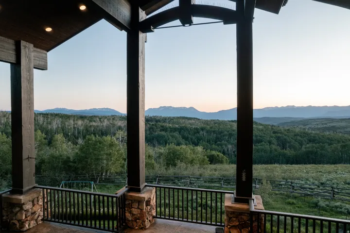 Spacious covered deck featuring substantial timber columns with stone bases and metal railings