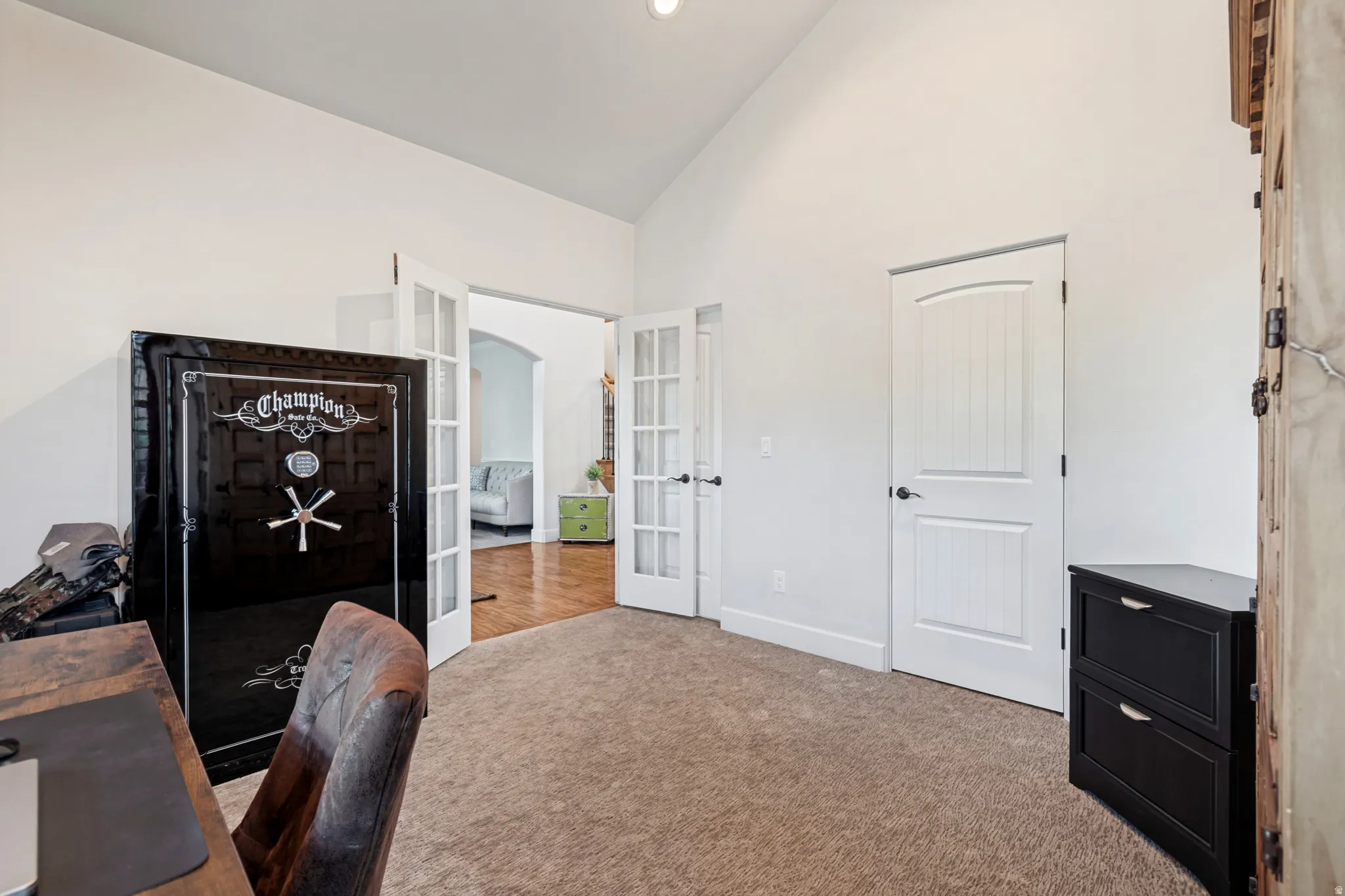 Carpeted office with vaulted ceilings, double French doors with glass panels, storage closet, and private access to a bathroom. Can be easily converted into a 5th bedroom for the home.
