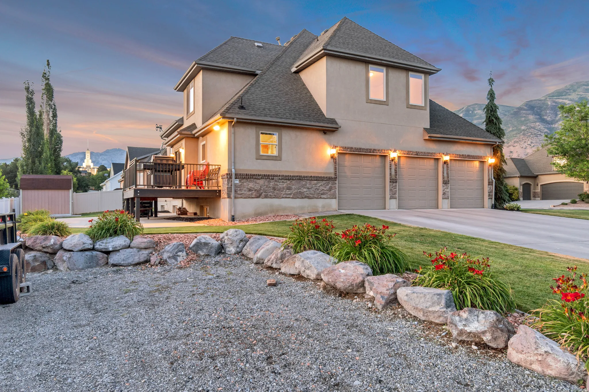 Stucco exterior with stone accents, a three-car garage, a rear deck, and RV parking.