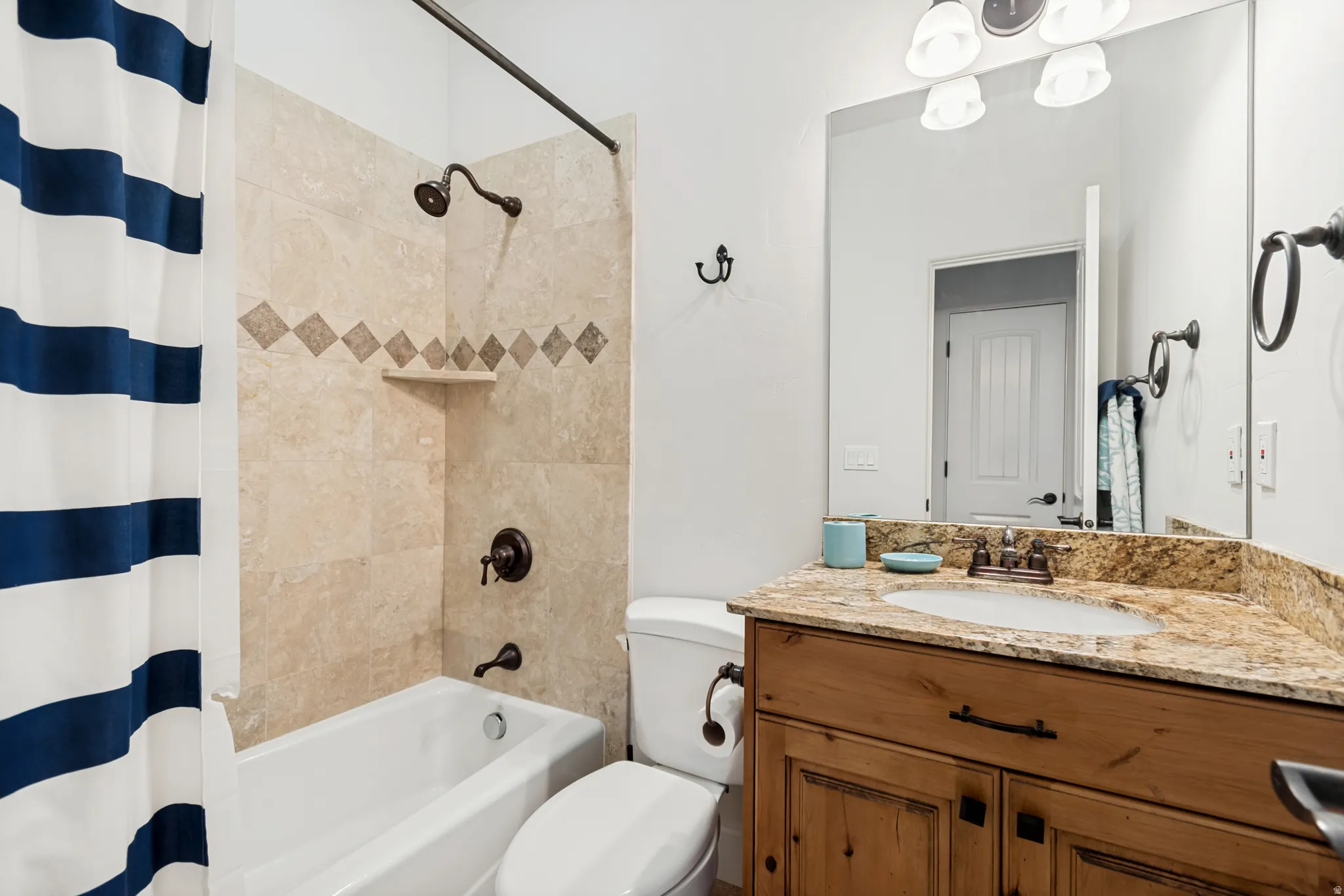 Bathroom for upstairs bedroom #1 featuring a tub and shower combination with tile surround and vanity with granite countertop.