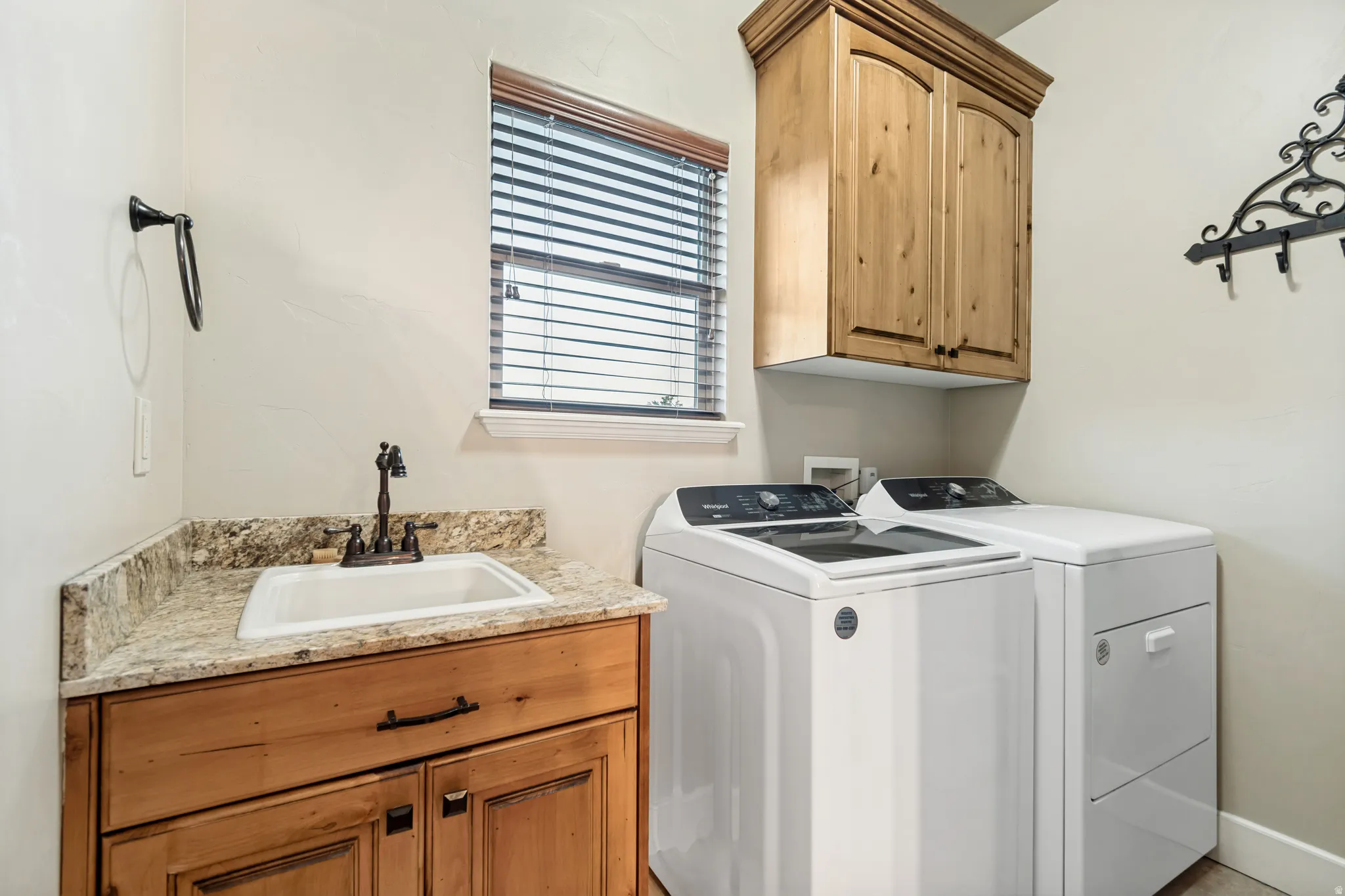 Laundry room off of the kitchen with rinsing sink and storage cabinet.