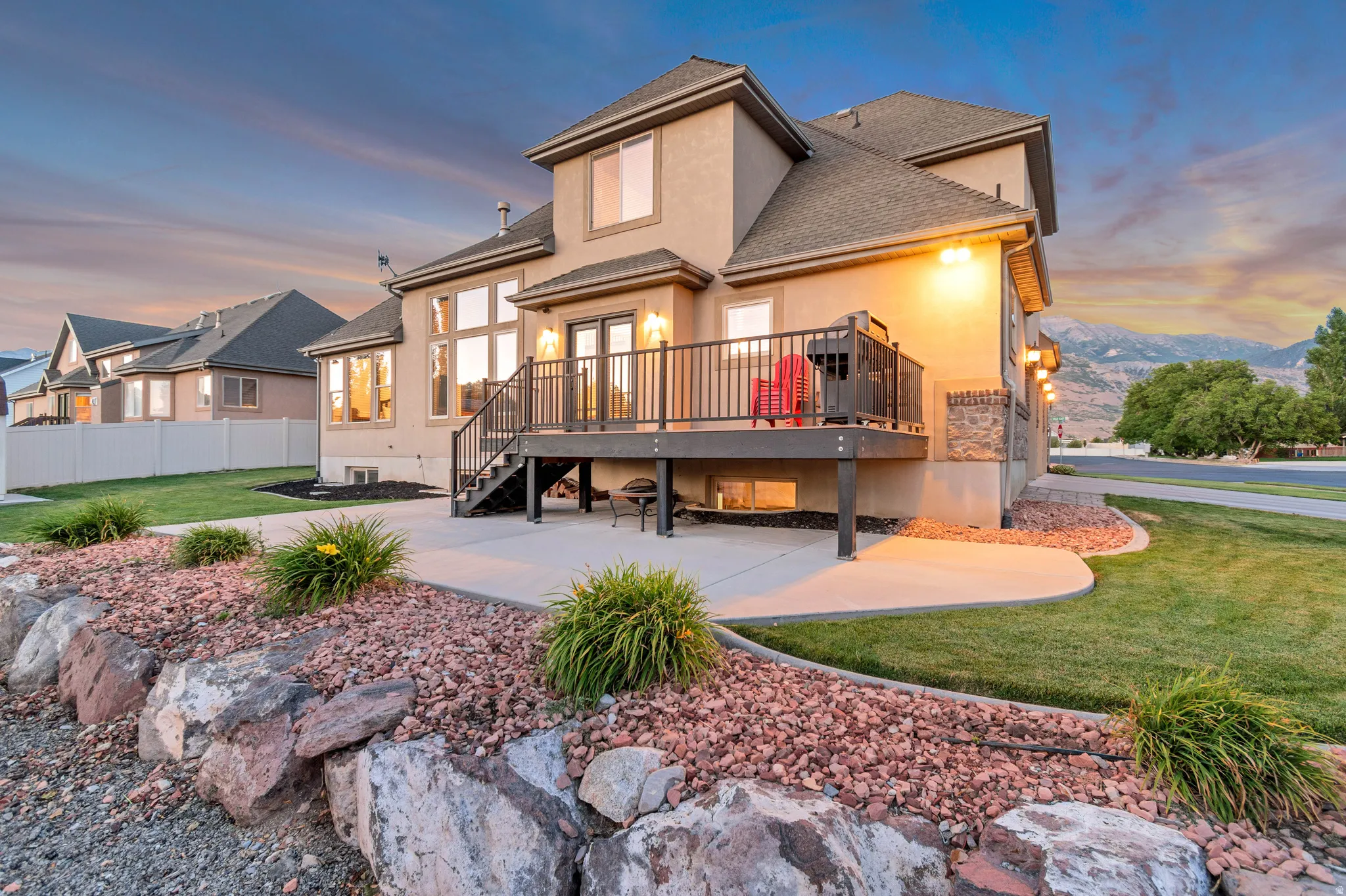 Rear exterior featuring a deck, stucco siding, and a stone accent wall.