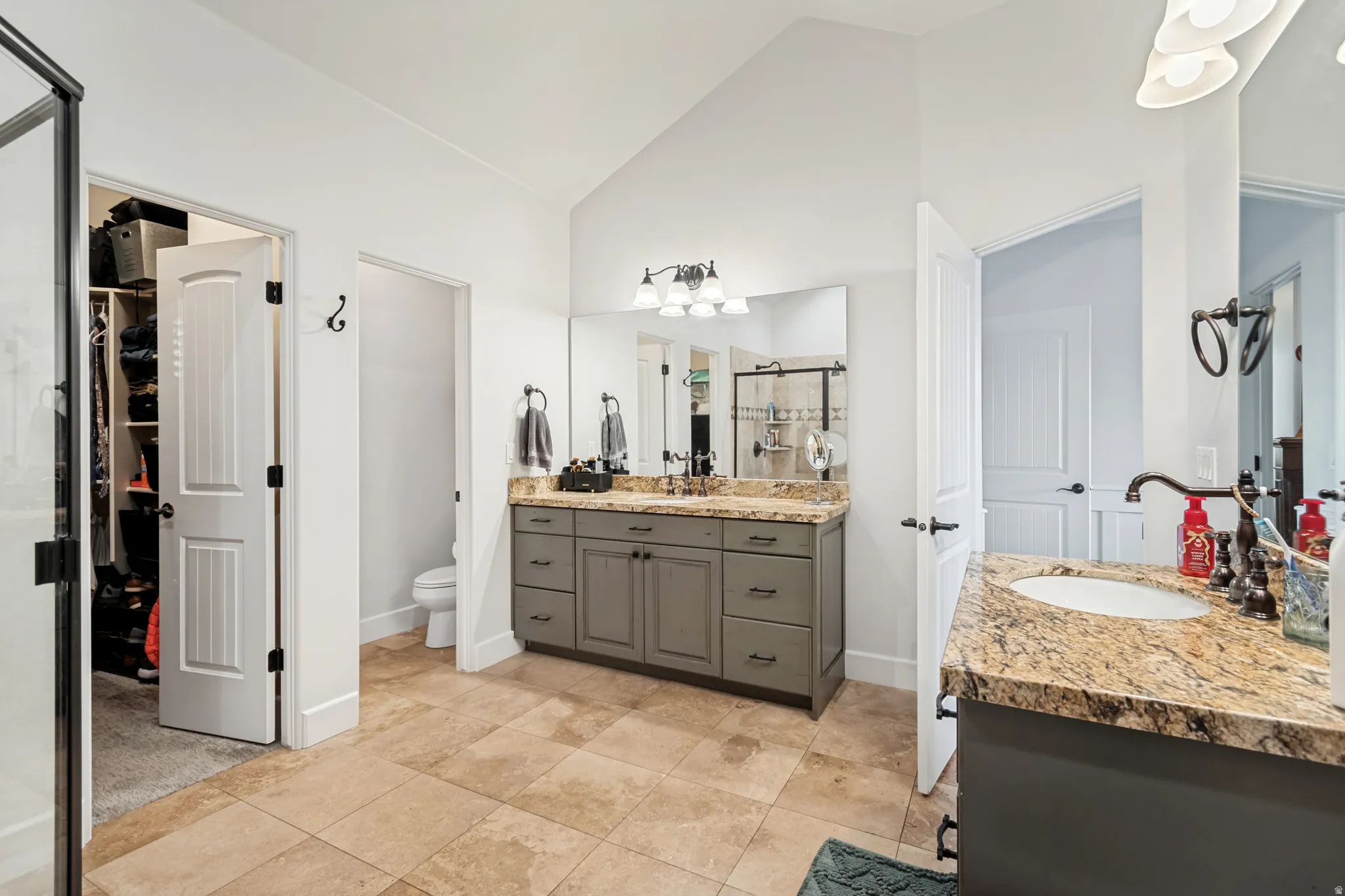 Spacious bathroom featuring dual vanities with granite countertops, undermount sinks, dark bronze fixtures, and walk-in closet.