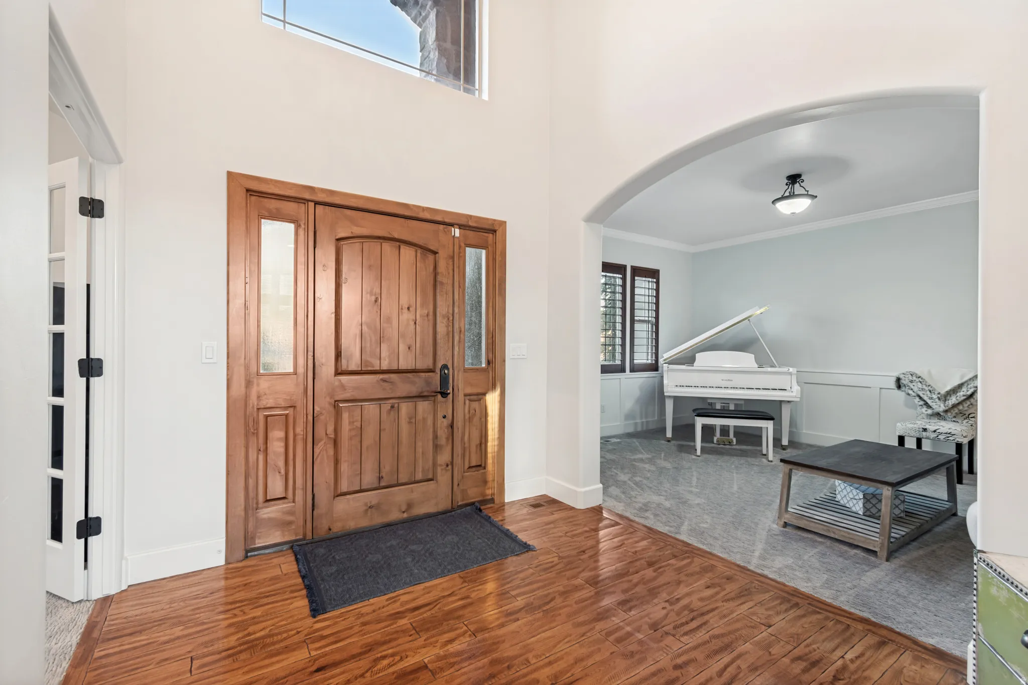 Entryway featuring hardwood flooring, vaulted ceiling, and a formal living room.