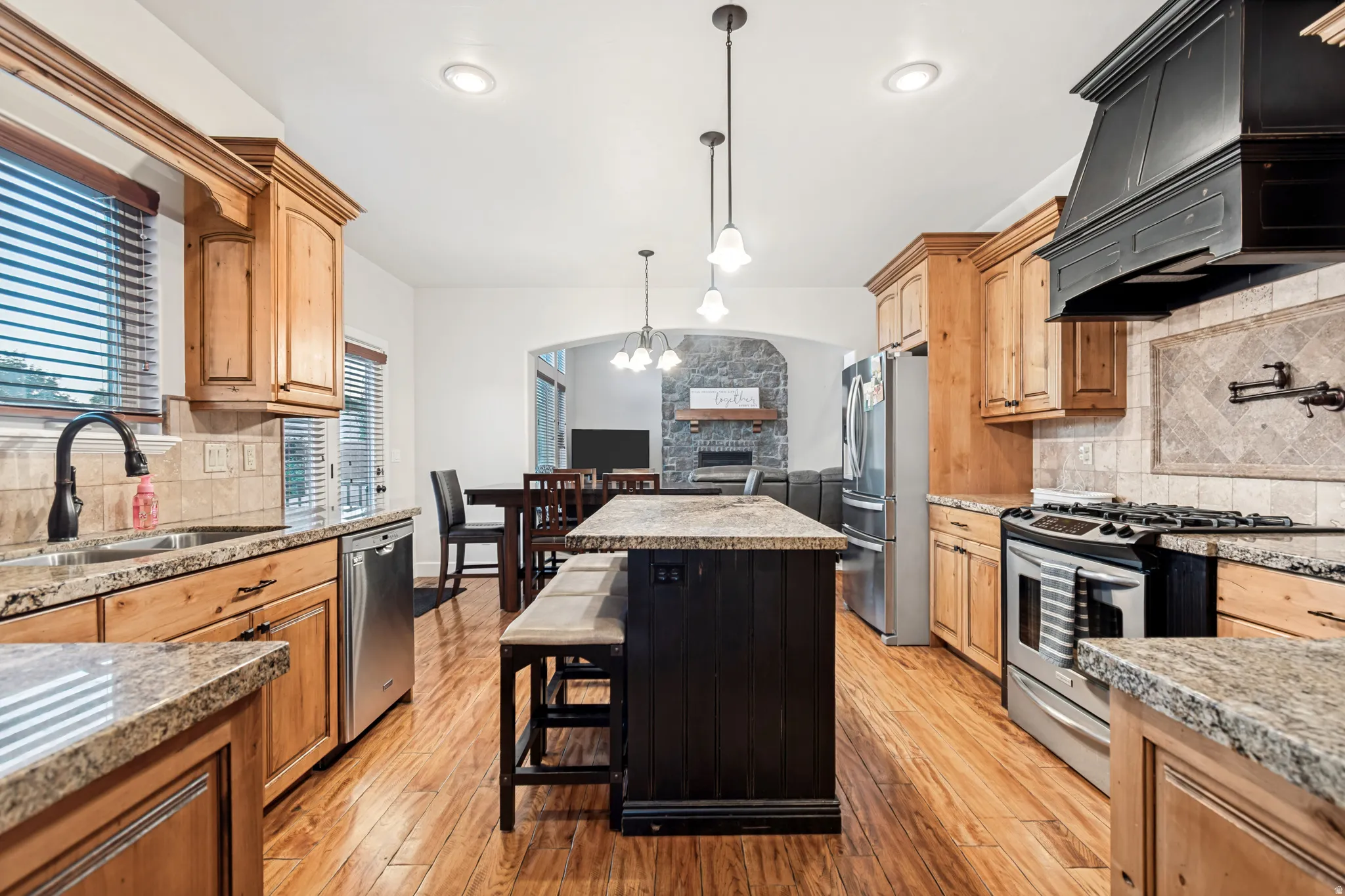 Spacious kitchen featuring light wood cabinetry, granite countertops, pendant lighting, and an abundance of cabinet storage.
