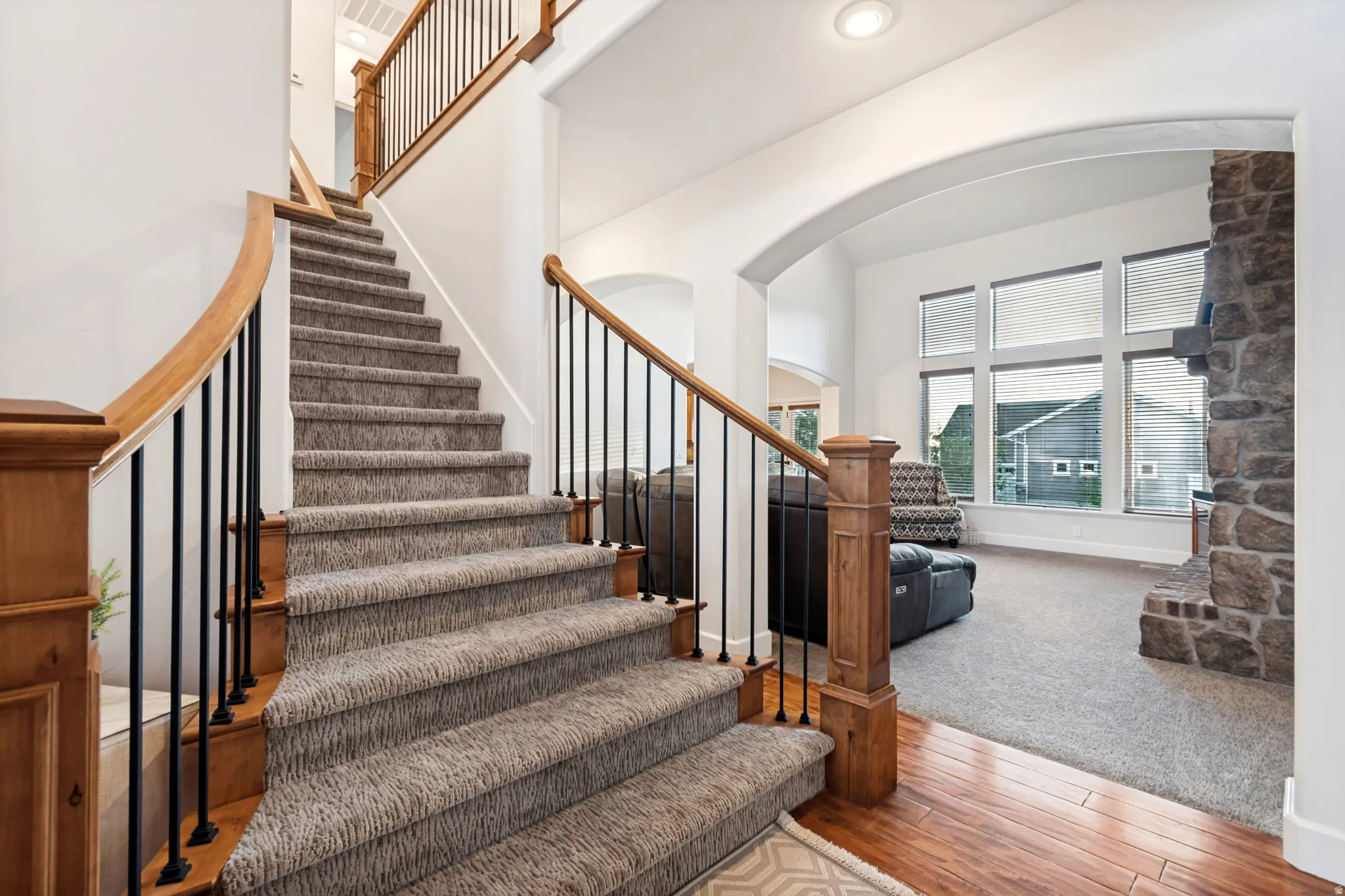 Carpeted staircase with wood handrails and black metal balusters.