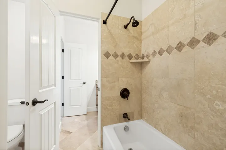 Jack and Jill bathroom for upstairs bedrooms #2 and 3, featuring light-toned tiled walls with a decorative accent band