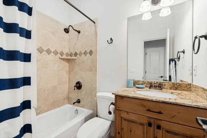 Bathroom for upstairs bedroom #1 featuring a tub and shower combination with tile surround and vanity with granite countertop.