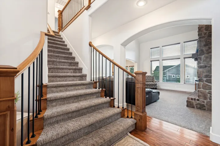 Carpeted staircase with wood handrails and black metal balusters.