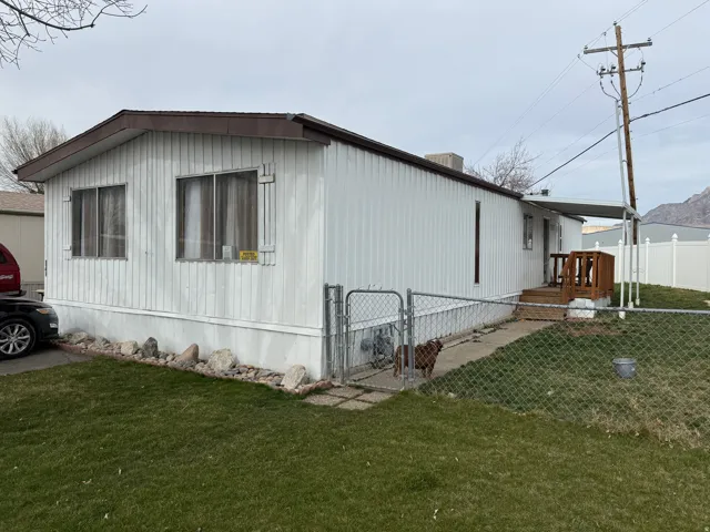 Manufactured home featuring white vertical siding and a brown shingled roof