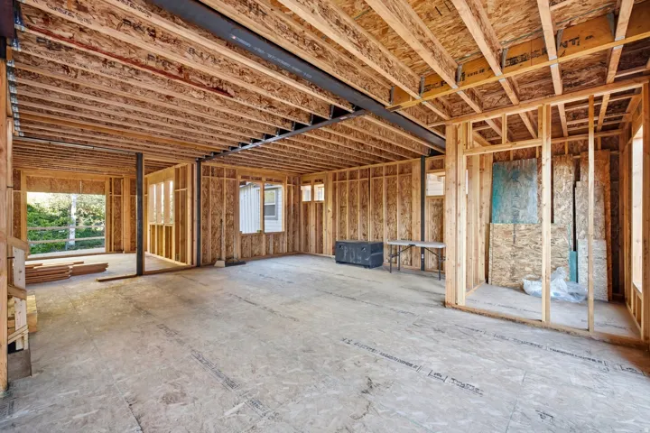 Unfinished interior with exposed wood framing, open ceiling joists, and a steel support beam