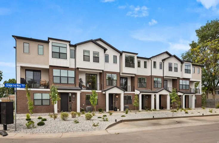 Contemporary multi-story townhome featuring a mixed-material facade of brick, stucco, and horizontal siding