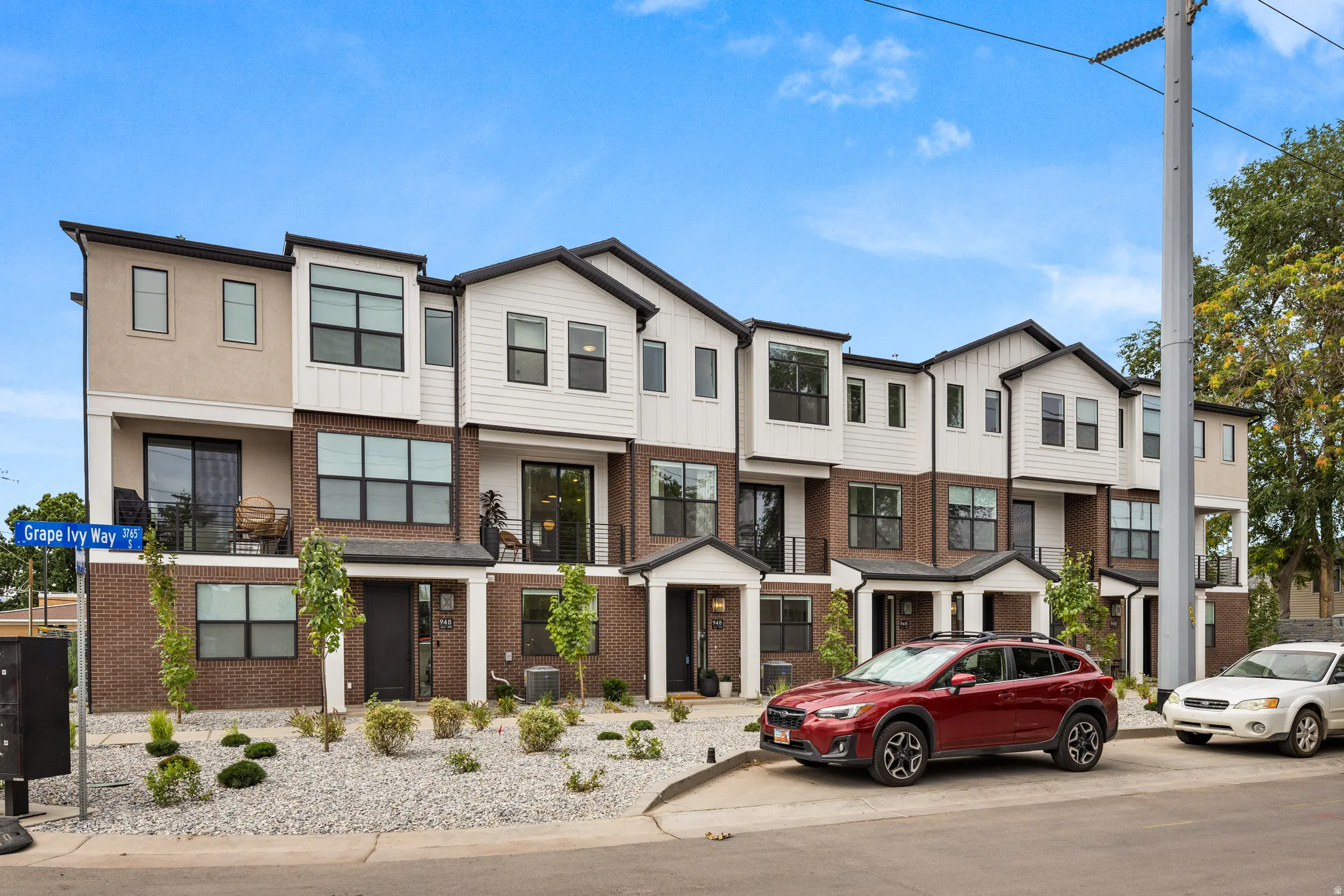 Modern townhome facade featuring a multi-material exterior with brick, horizontal siding, and stucco finishes