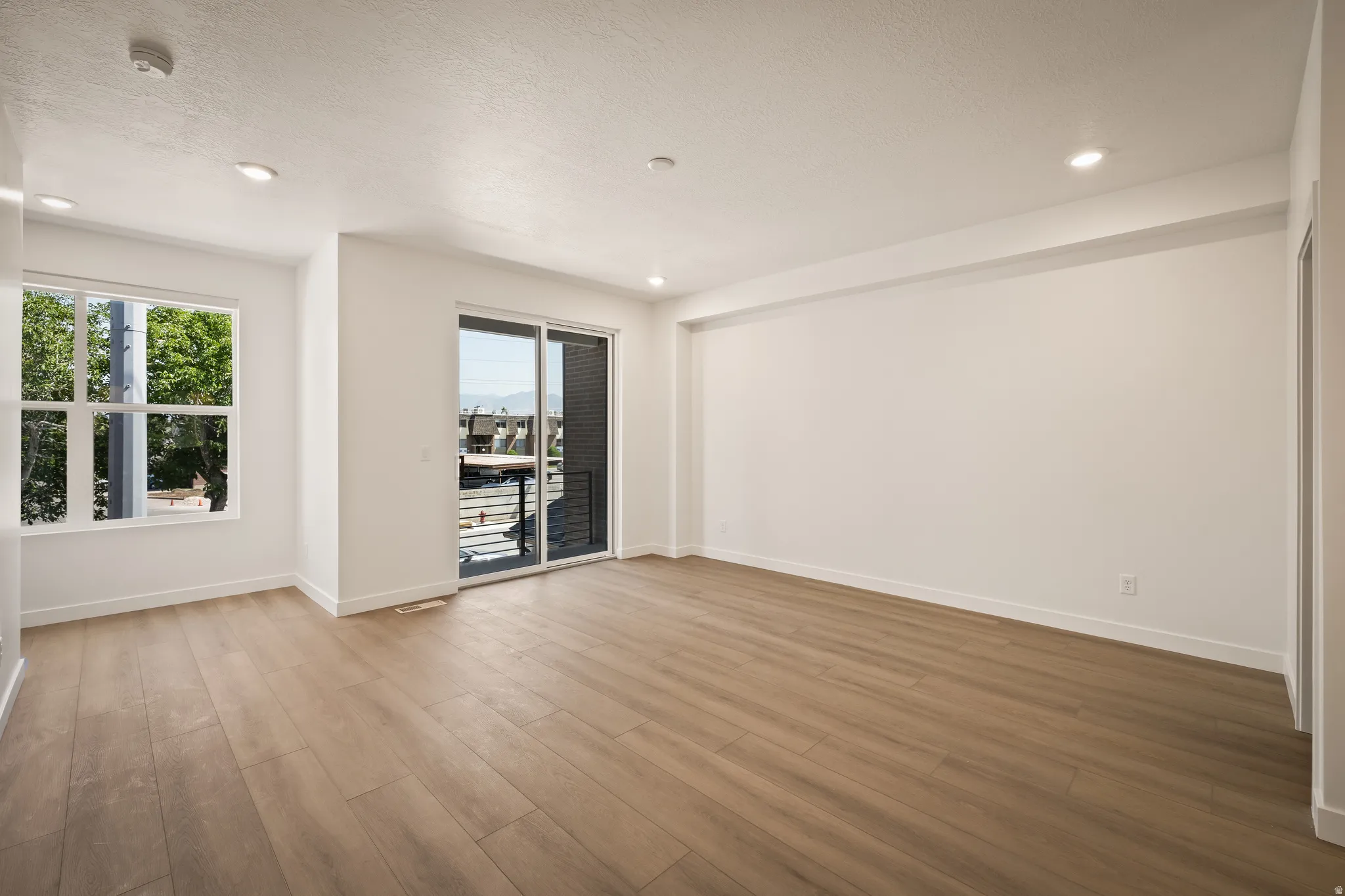 Spacious room featuring wood-finish flooring, recessed lighting, and white walls