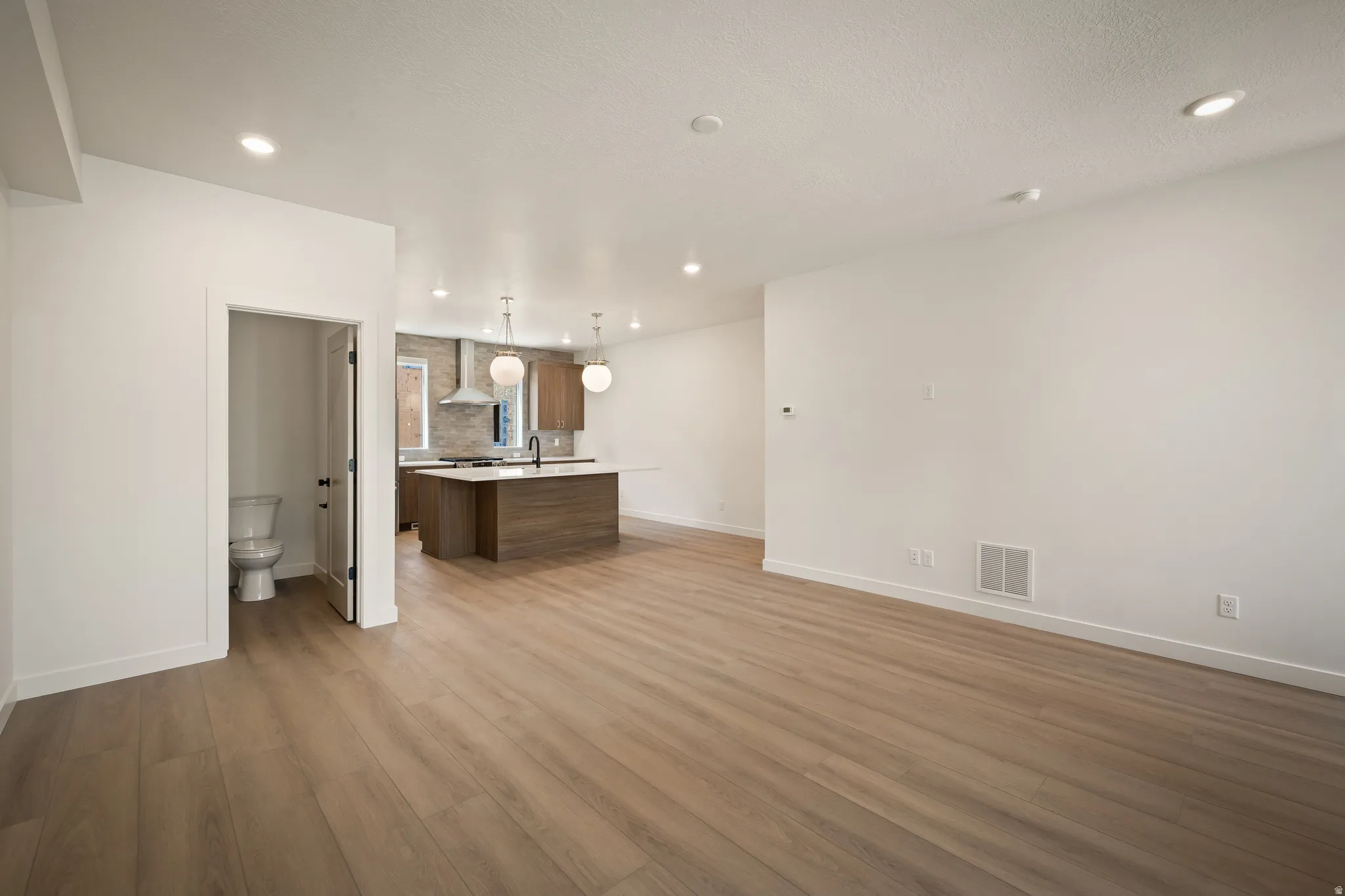 Open-concept living area featuring wood-finish flooring, recessed lighting, and a modern kitchen