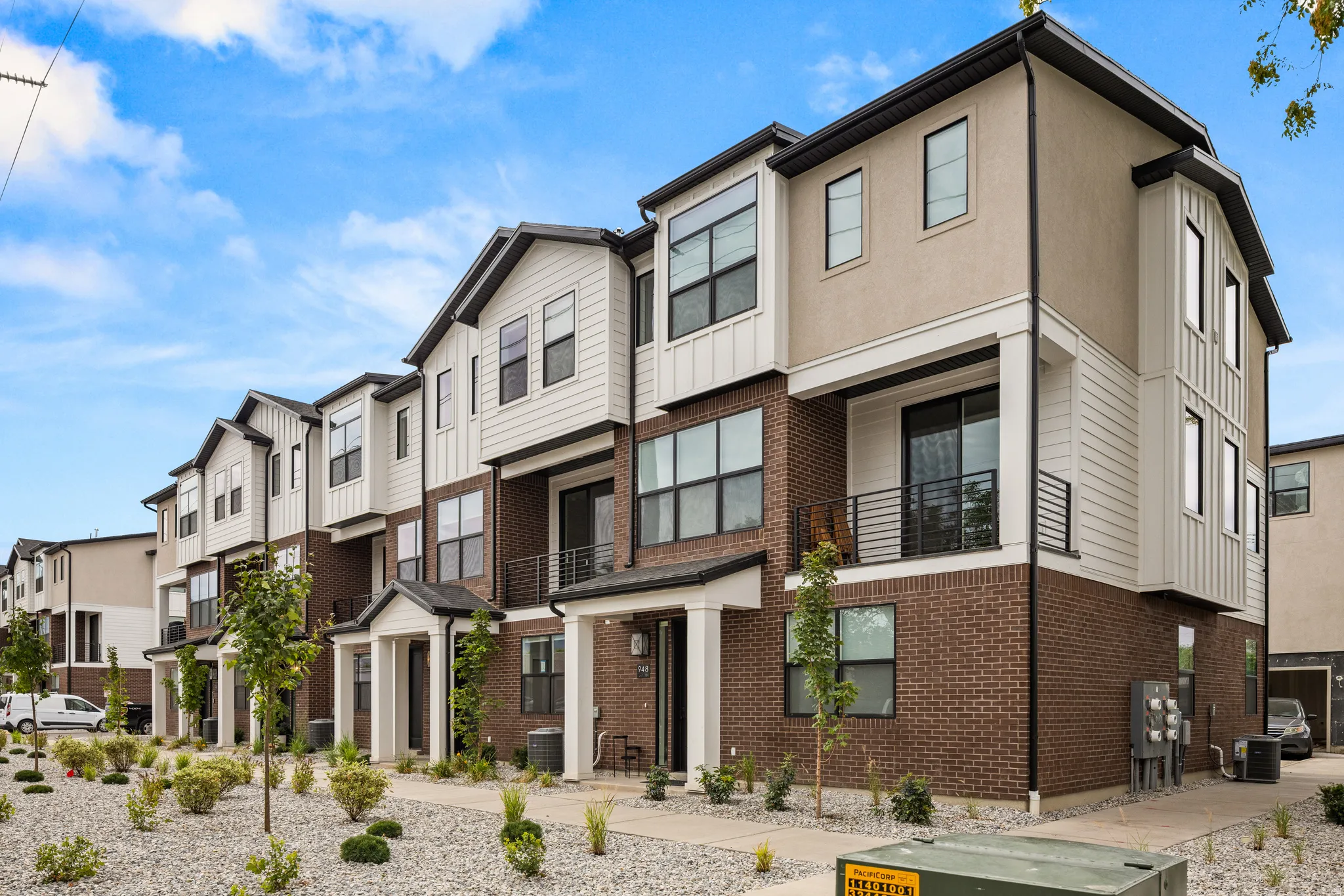 Contemporary townhome exterior featuring a multi-material facade with brick, horizontal siding, and stucco finishes