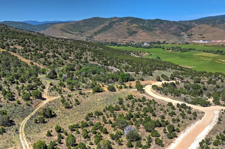 Expansive undeveloped terrain featuring rolling hills, scattered natural vegetation, and distant mountain ranges