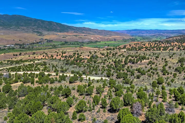 Expansive terrain featuring natural vegetation, distant mountains, and a valley with agricultural fields