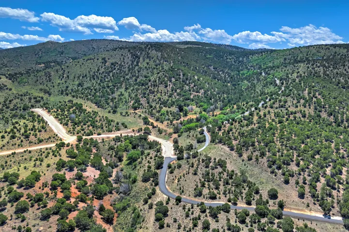 Expansive land featuring paved and unpaved roadways, surrounded by a natural landscape of varied terrain and abundant trees