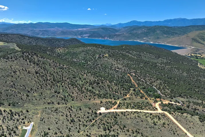Expansive land offering a mountainous landscape, a prominent lake, and visible dirt roads
