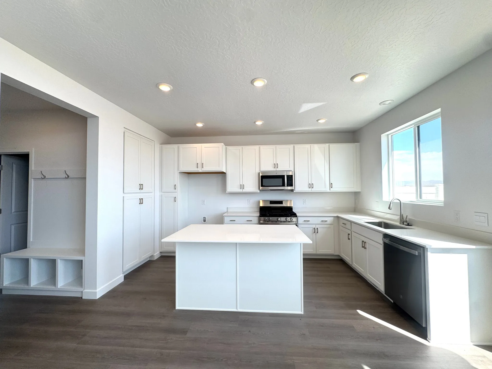 Modern kitchen featuring white cabinetry, a central island, stainless steel appliances, and wood-finish flooring
