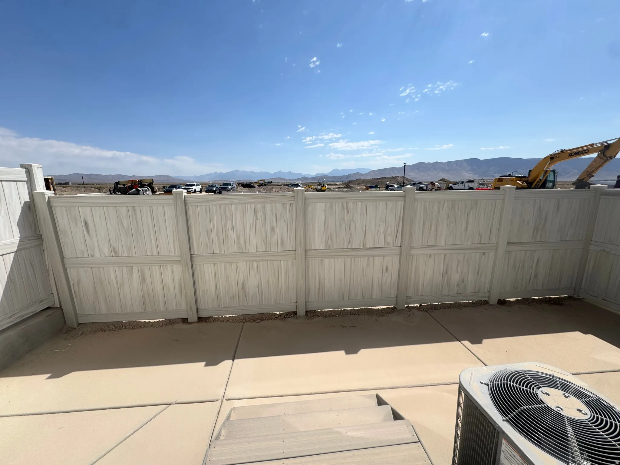 Concrete patio area featuring a light-colored privacy fence and a split-level design with a step