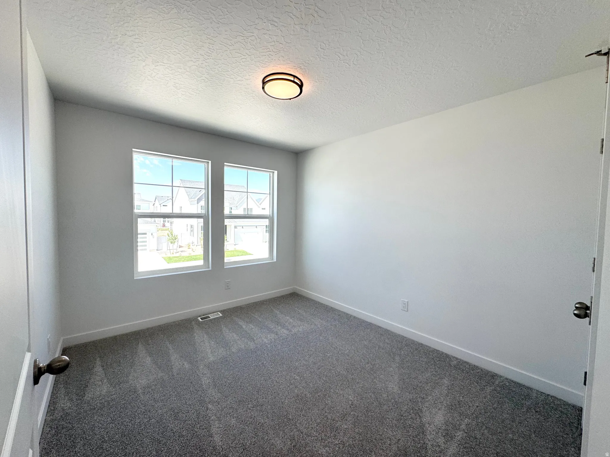 Room featuring two large windows with white trim, gray carpet, white walls, and a contemporary flush-mount ceiling light