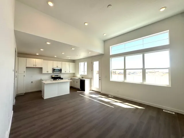 Open-concept living area featuring a modern kitchen with white cabinetry, stainless steel appliances, and a central island