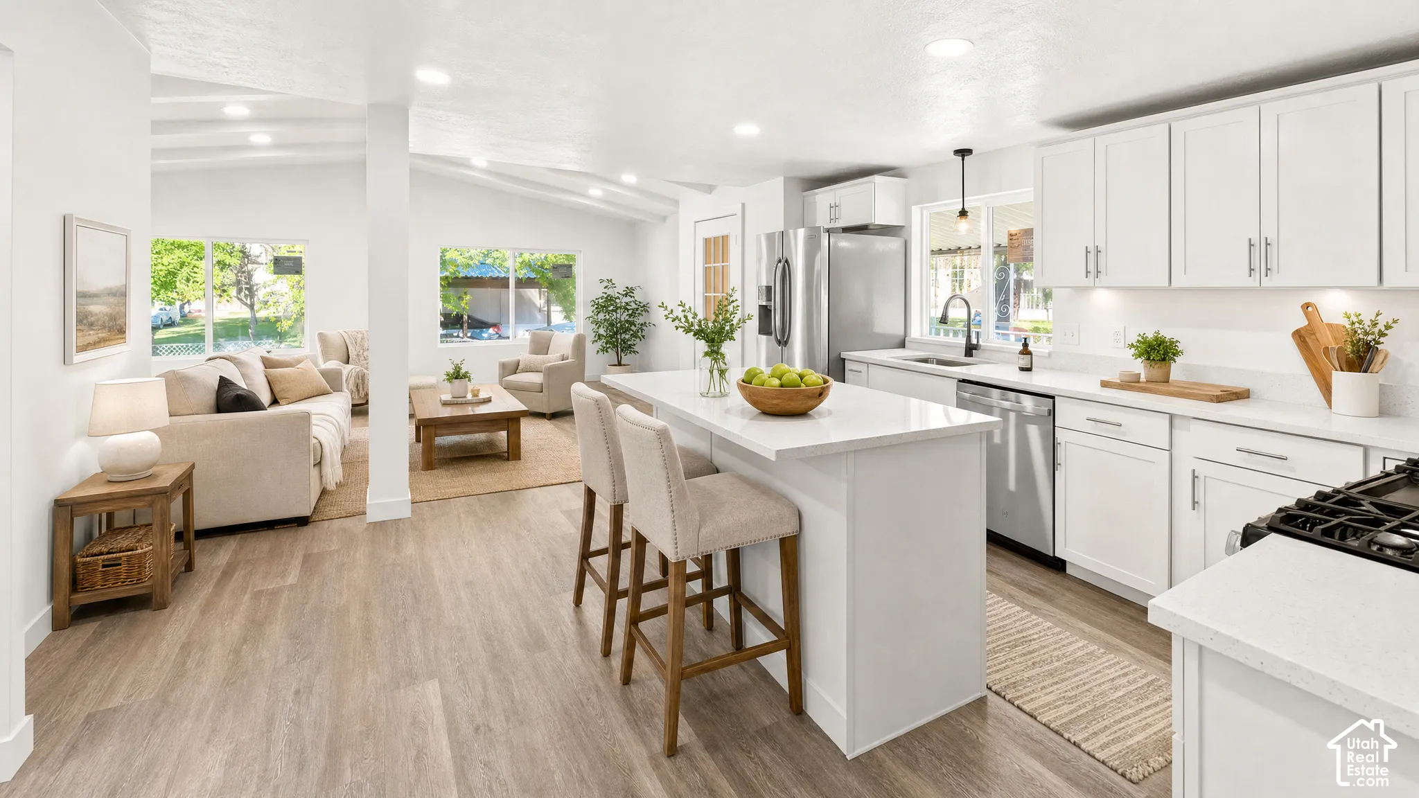 Modern kitchen featuring white cabinetry, stainless steel appliances, a center island with bar seating, and light-colored countertops