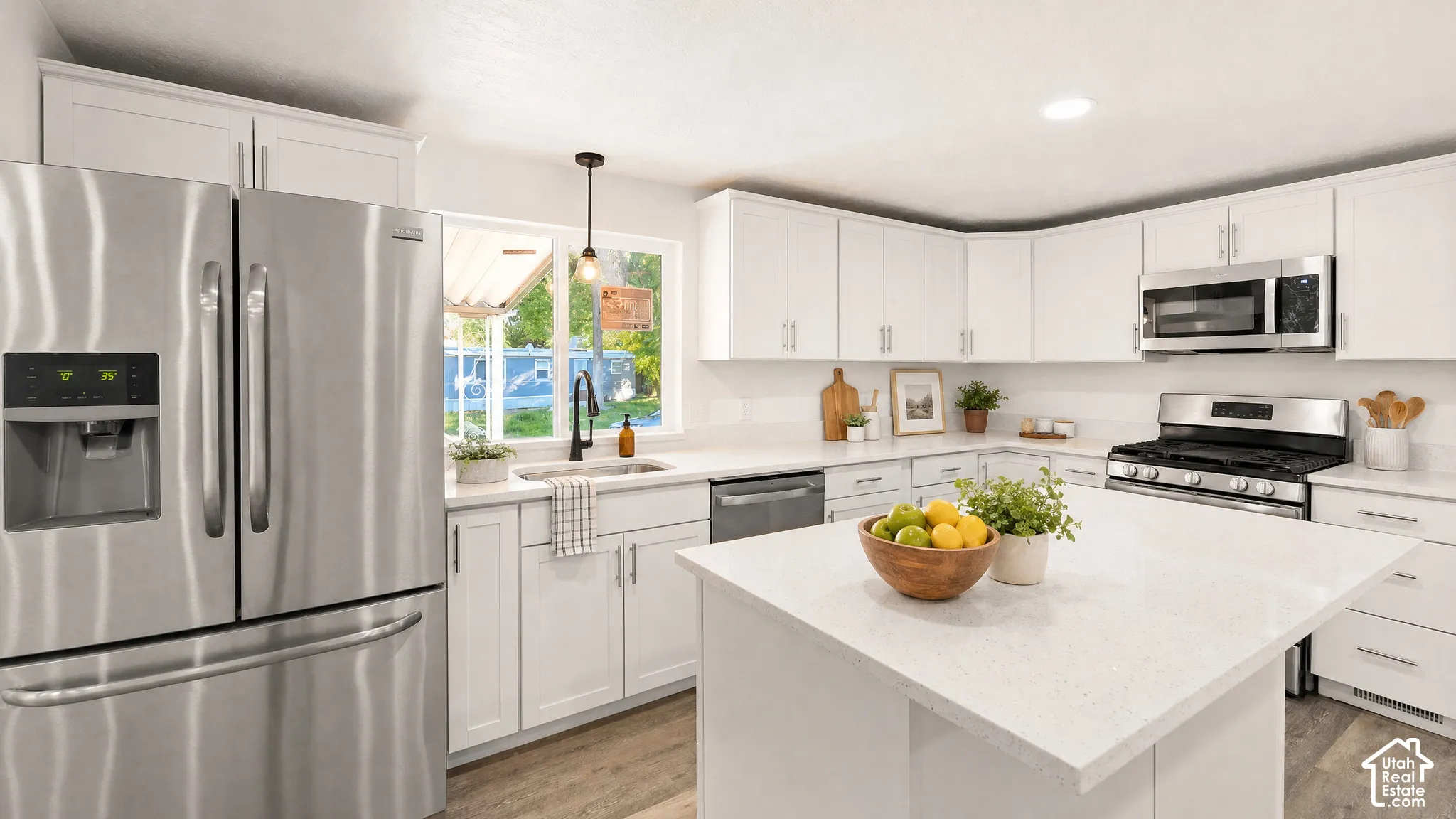 Modern kitchen featuring white shaker cabinetry, stainless steel appliances, light-toned countertops, a central island, and wood-finish flooring
