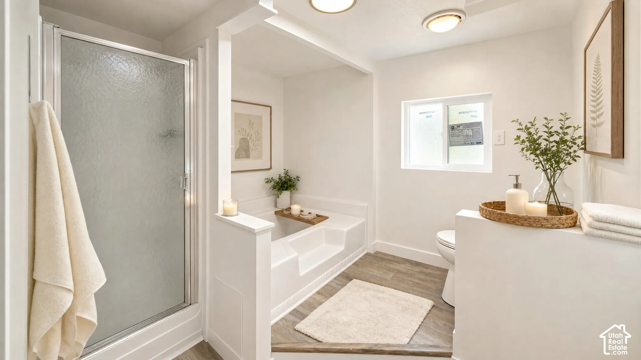 Bathroom featuring a built-in shower with frosted glass enclosure, an integrated soaking tub, wood-finish flooring, a toilet, and a window
