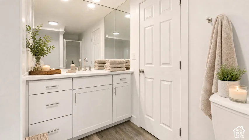 Bathroom vanity featuring white cabinetry with brushed nickel hardware, a white countertop, and a full-wall mirror