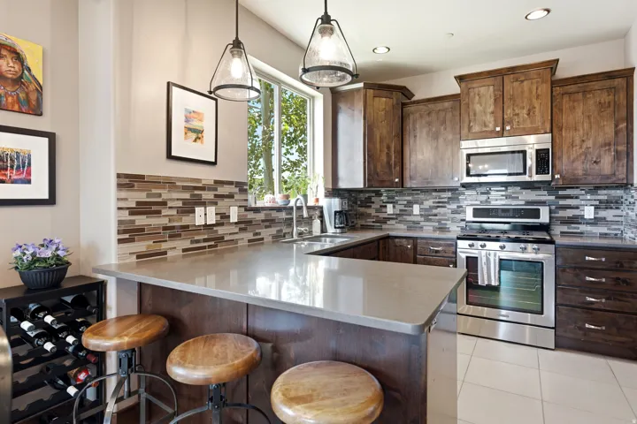 Kitchen featuring wood cabinetry, stainless steel appliances, a multi-tone tile backsplash, light-toned countertops, and recessed lighting