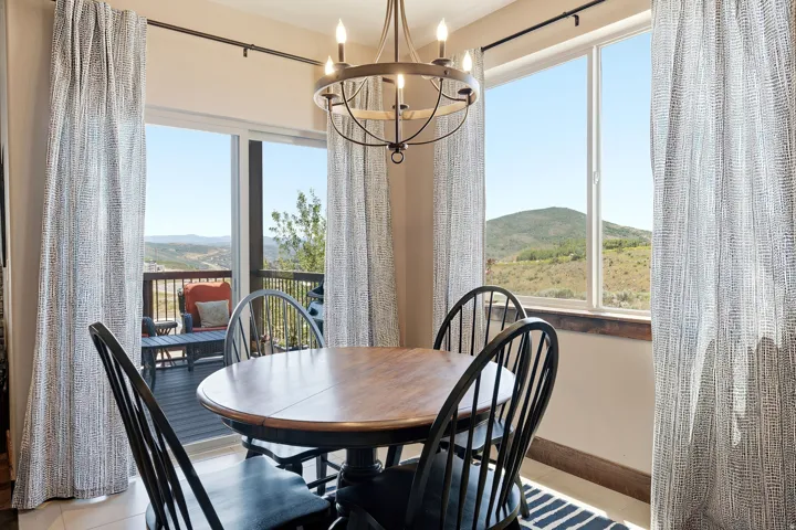 Sliding glass door leading to an outdoor deck, large window with mountain scenery, and a wrought iron chandelier