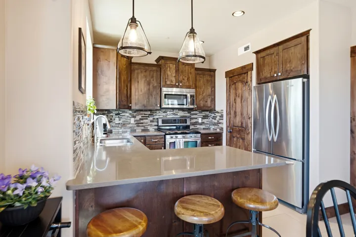 Modern kitchen featuring rich wood cabinetry, stainless steel appliances, and a quartz-topped island with seating