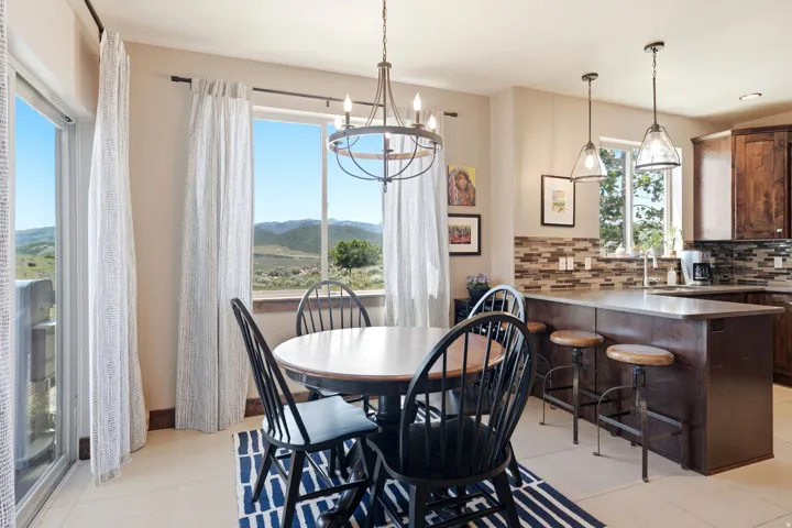 Open-concept dining and kitchen area flooded with natural light through expansive glass doors and windows framing mountain vistas