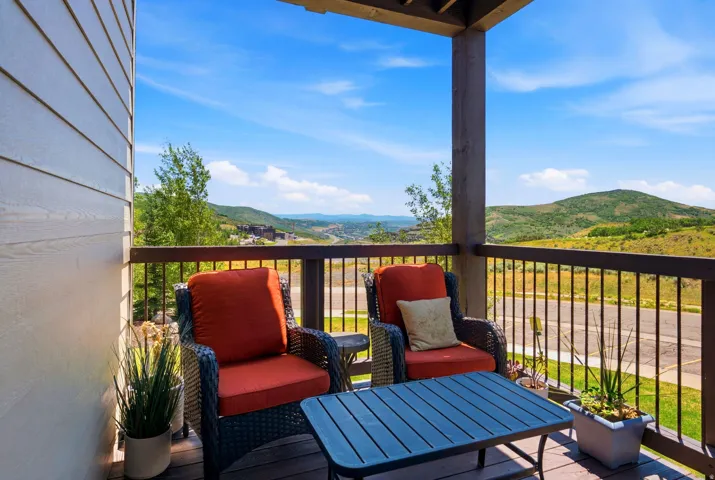 Elevated deck featuring metal railings, comfortable seating arrangement, and expansive panoramic landscape vistas