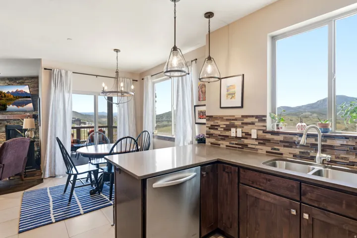 Contemporary kitchen and dining area featuring stainless steel appliances, dark wood cabinetry, and a multi-tiered island with waterfall countertop