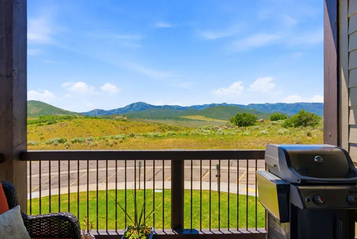 Expansive covered deck with metal railings overlooking sprawling meadowland and distant mountain ranges