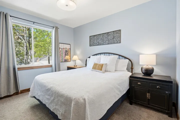 Serene primary bedroom showcasing a metal-frame bed, soft white bedding, and coordinating throw pillows