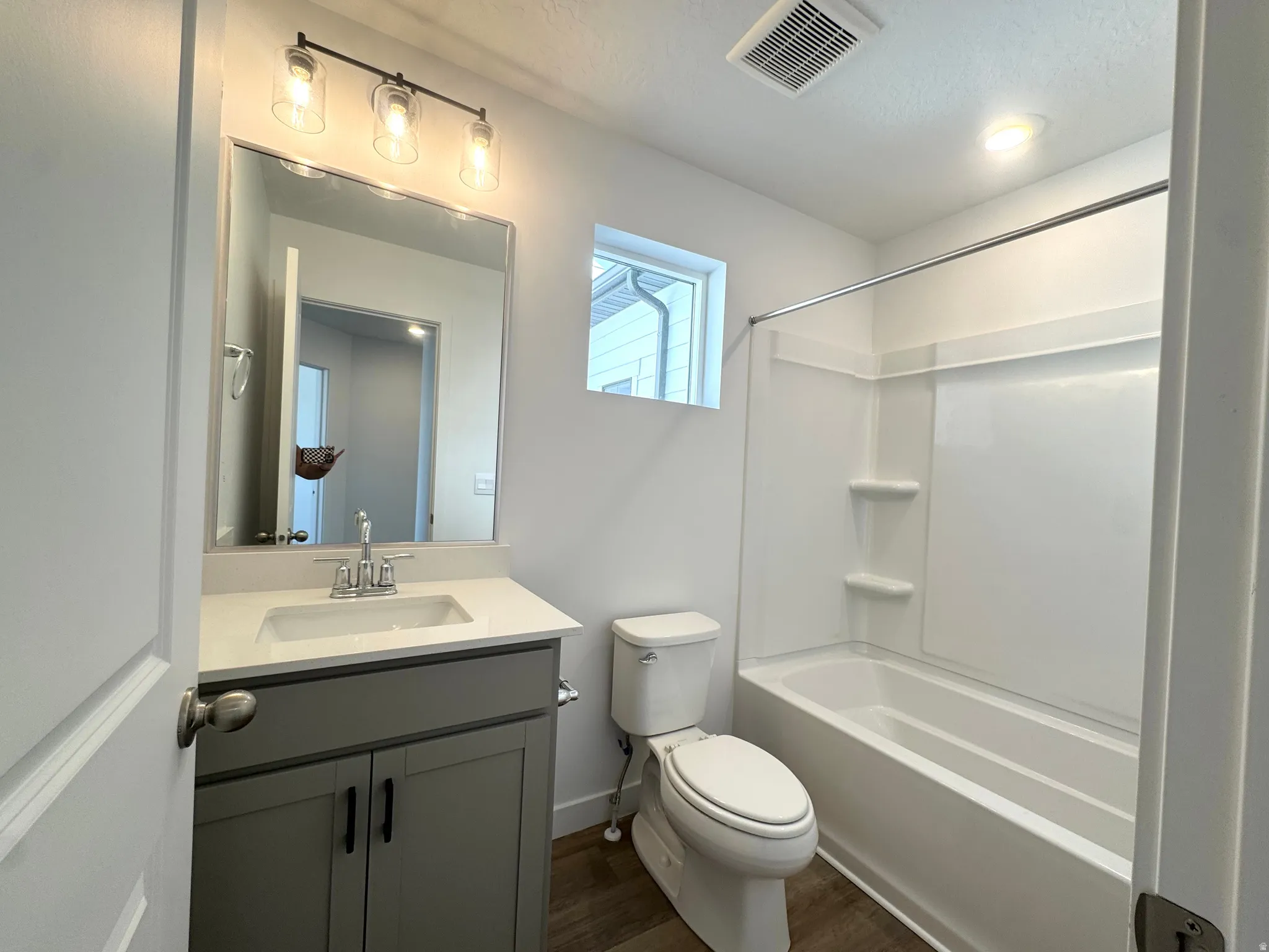 Bathroom featuring a single vanity with a light countertop and grey cabinetry, a full-size mirror, and a three-light fixture