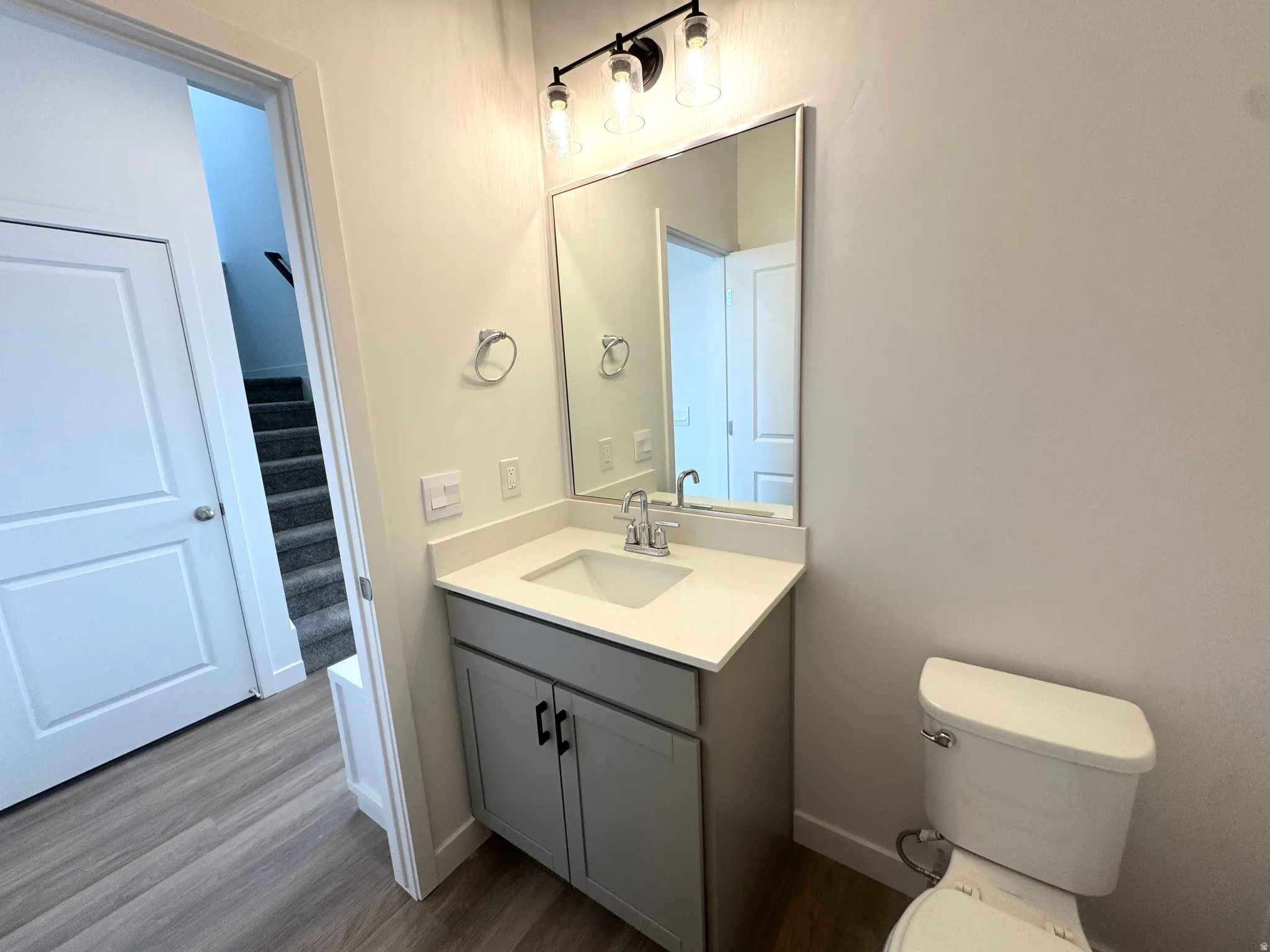 Powder bathroom featuring a light gray cabinet, white countertop with an integrated sink, and brushed nickel faucet