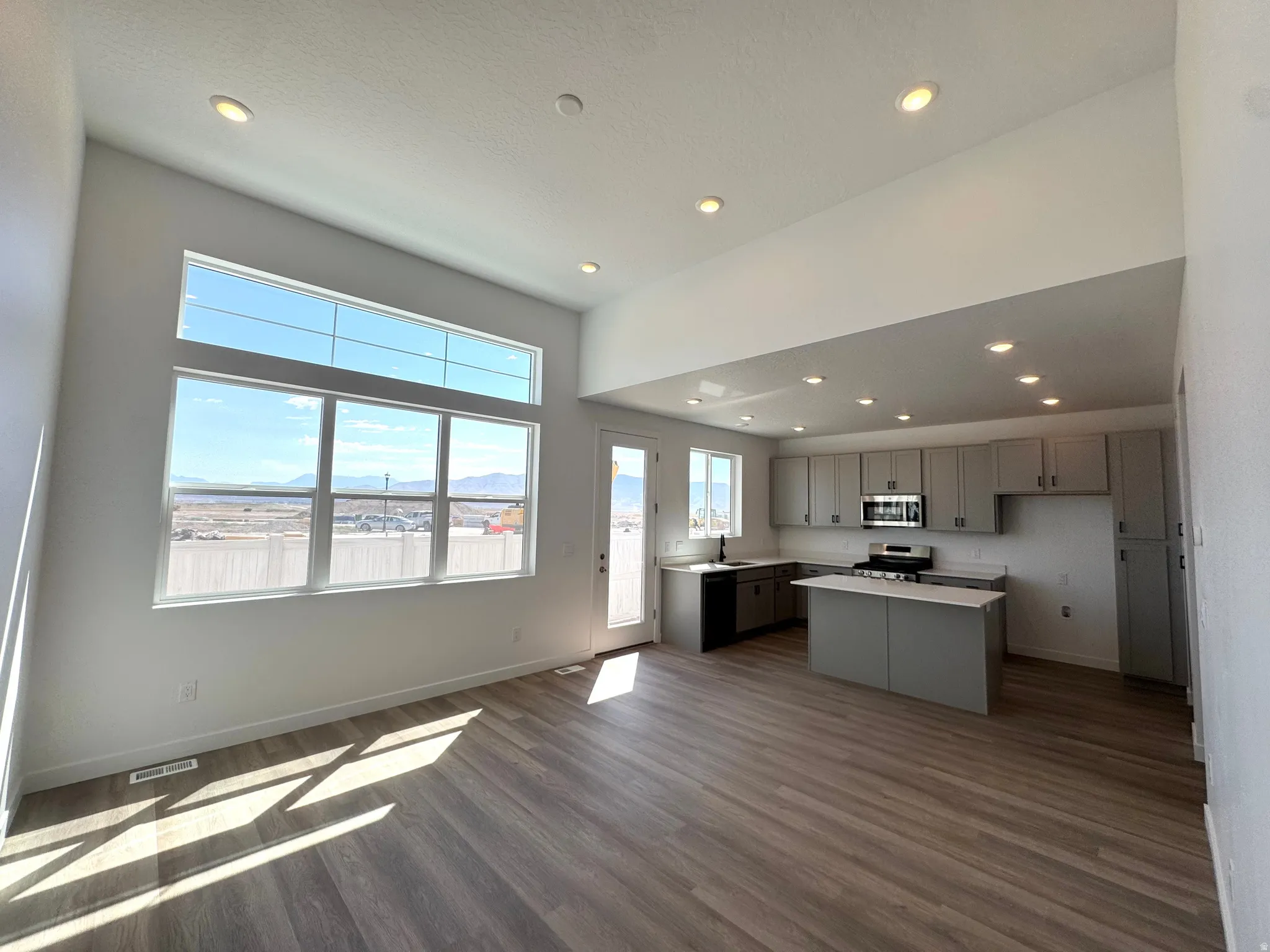 Open-concept living space with extensive natural light from a large window arrangement and a vaulted ceiling