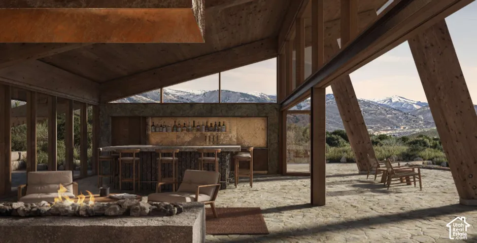 Expansive stone patio with an integrated fire pit, a built-in bar, wood-beam construction, and large glass paneling