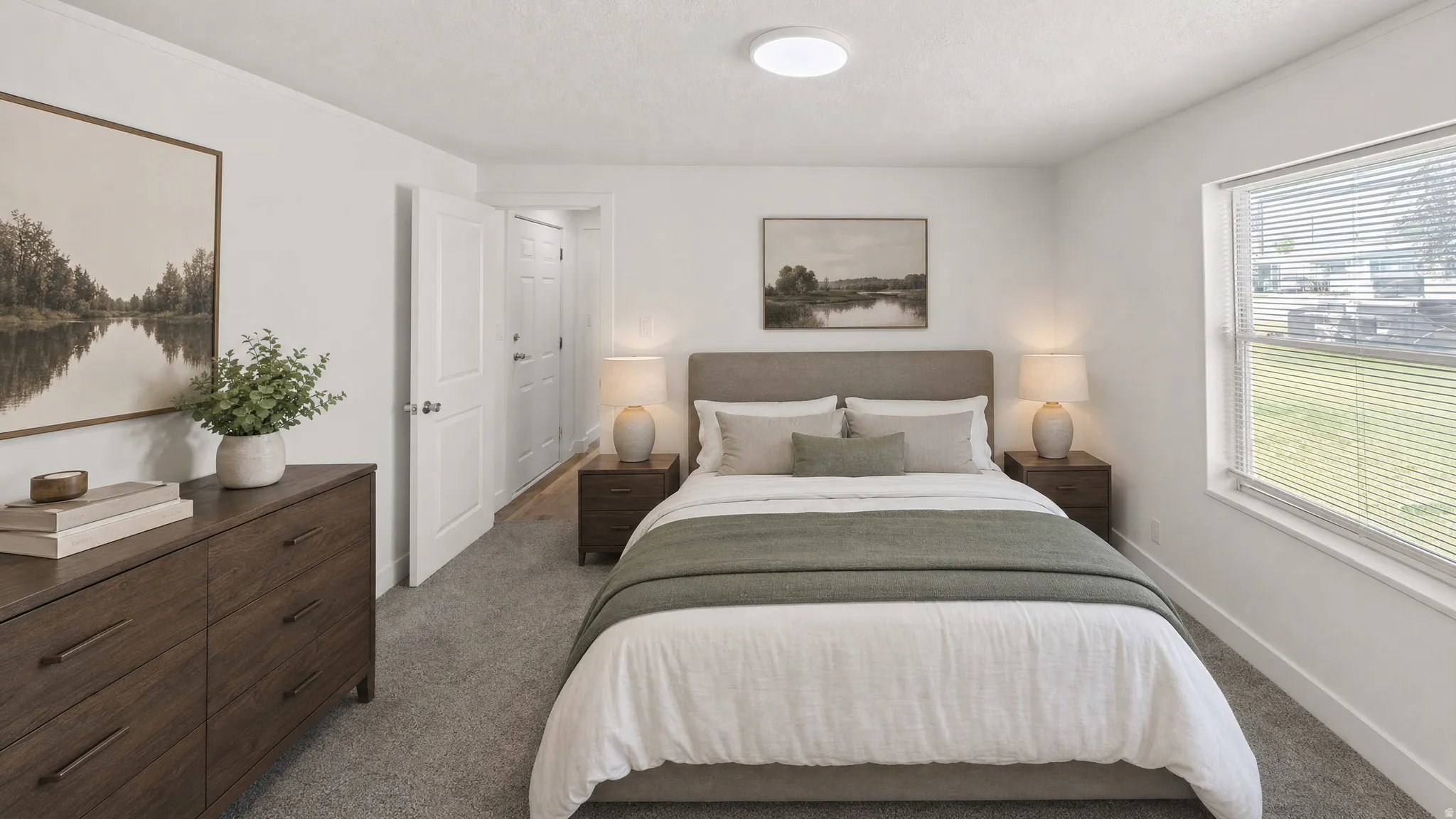 Carpeted bedroom featuring a large window with blinds, a ceiling-mounted light fixture, and two white interior doors