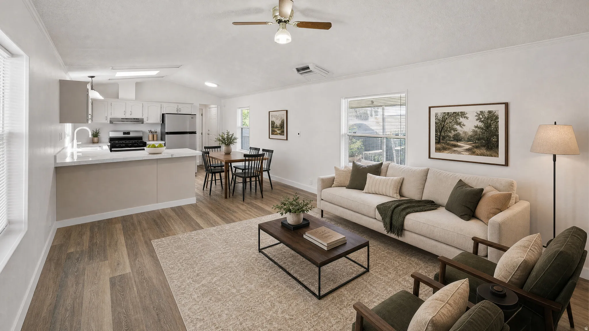 Open-concept living area featuring wood-finish flooring, a vaulted ceiling with a ceiling fan, and a kitchen with white cabinetry, a white countertop, and stainless steel appliances