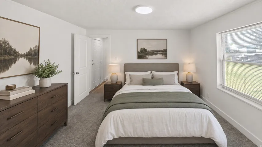 Carpeted bedroom featuring a large window with blinds, a ceiling-mounted light fixture, and two white interior doors
