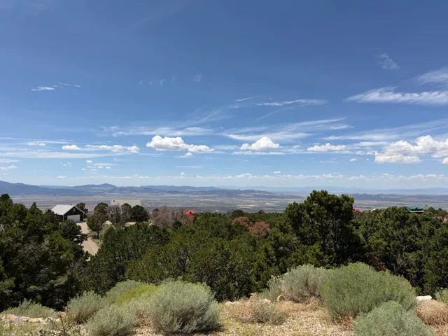 Expansive mountain and valley scenery under a broad blue sky with scattered clouds