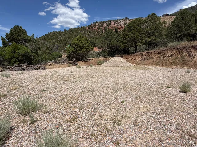 Expansive gravel pad with a gentle slope towards the wooded hillside