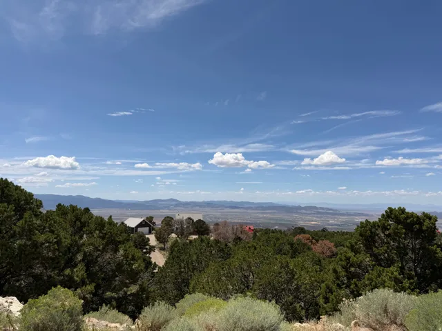 Expansive landscape featuring distant mountains, a wide valley, and a clear sky with scattered clouds